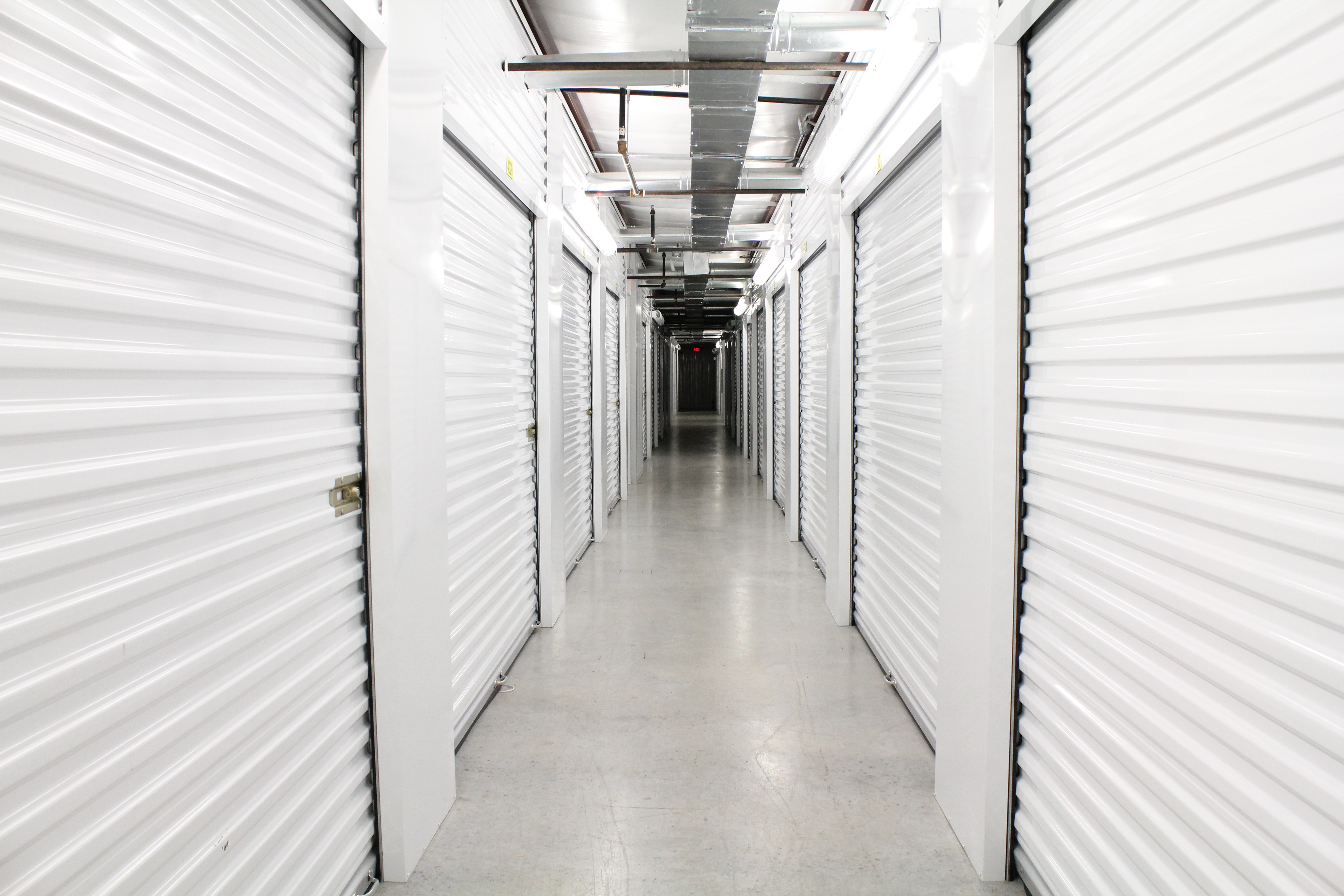 Secure, temperature-controlled hallway inside Harbor Point Storage, Vero Beach, with pristine white storage doors, elevator for easy access, and continuous security camera surveillance.