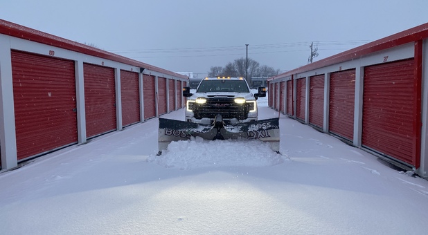 truck plowing snow between storage unit buildings