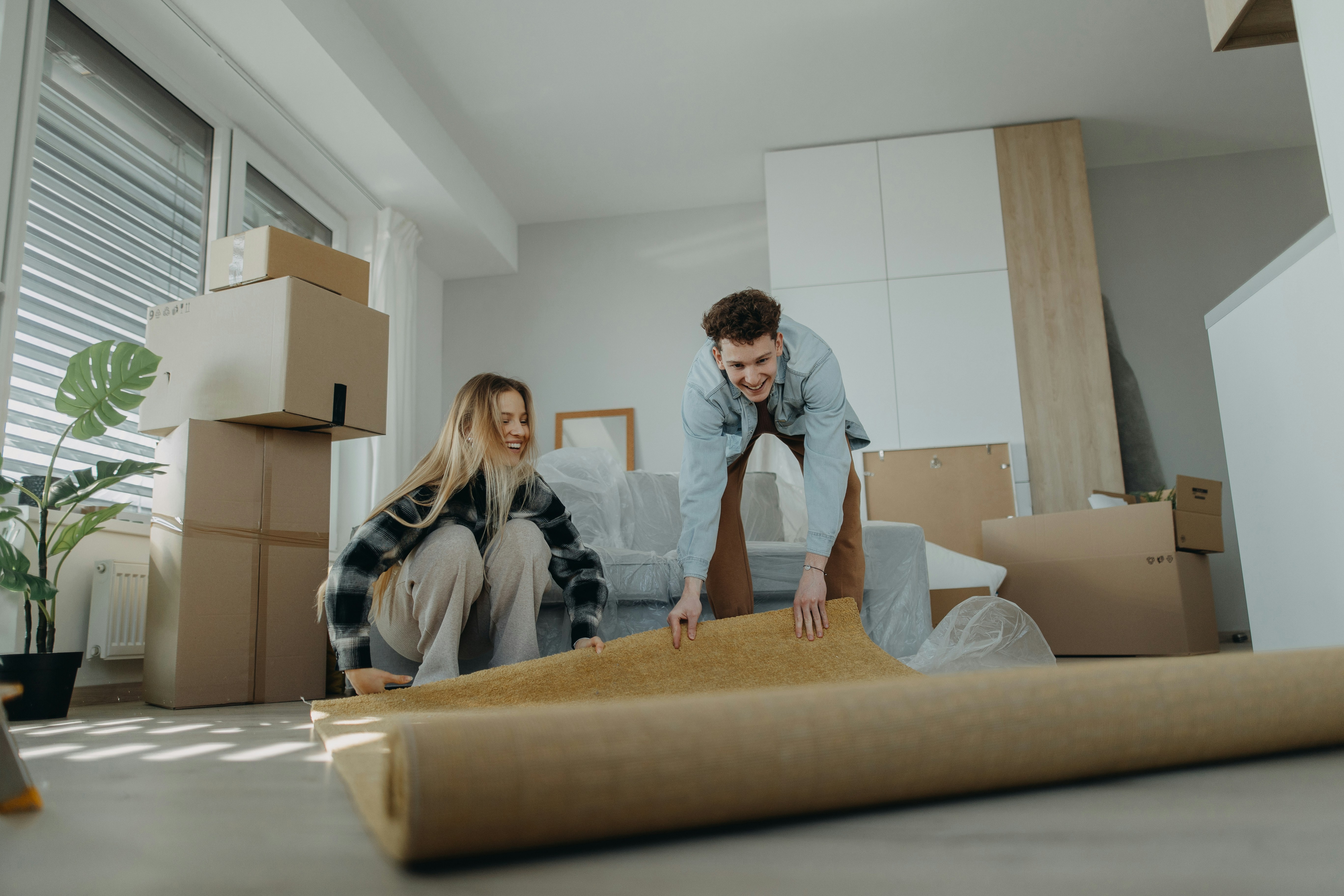 Couple unrolling carpet in their new apartment after moving to a new place