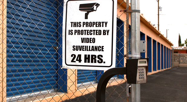 Security sign mounted to fence with storage building in the background