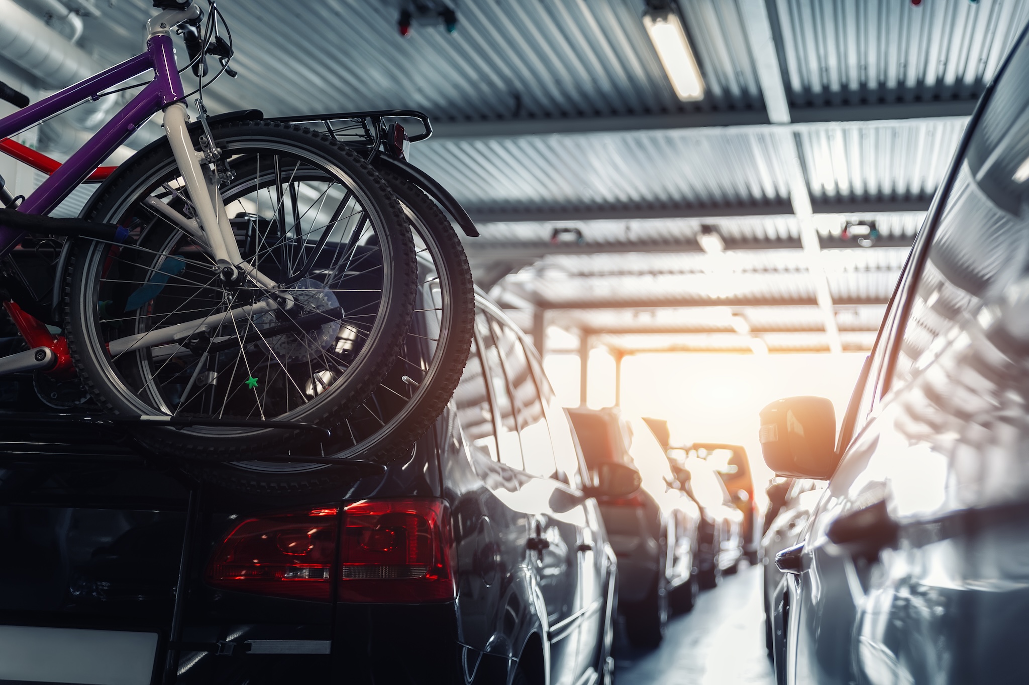 vehicles parked in building with a view of sunset outside open door.