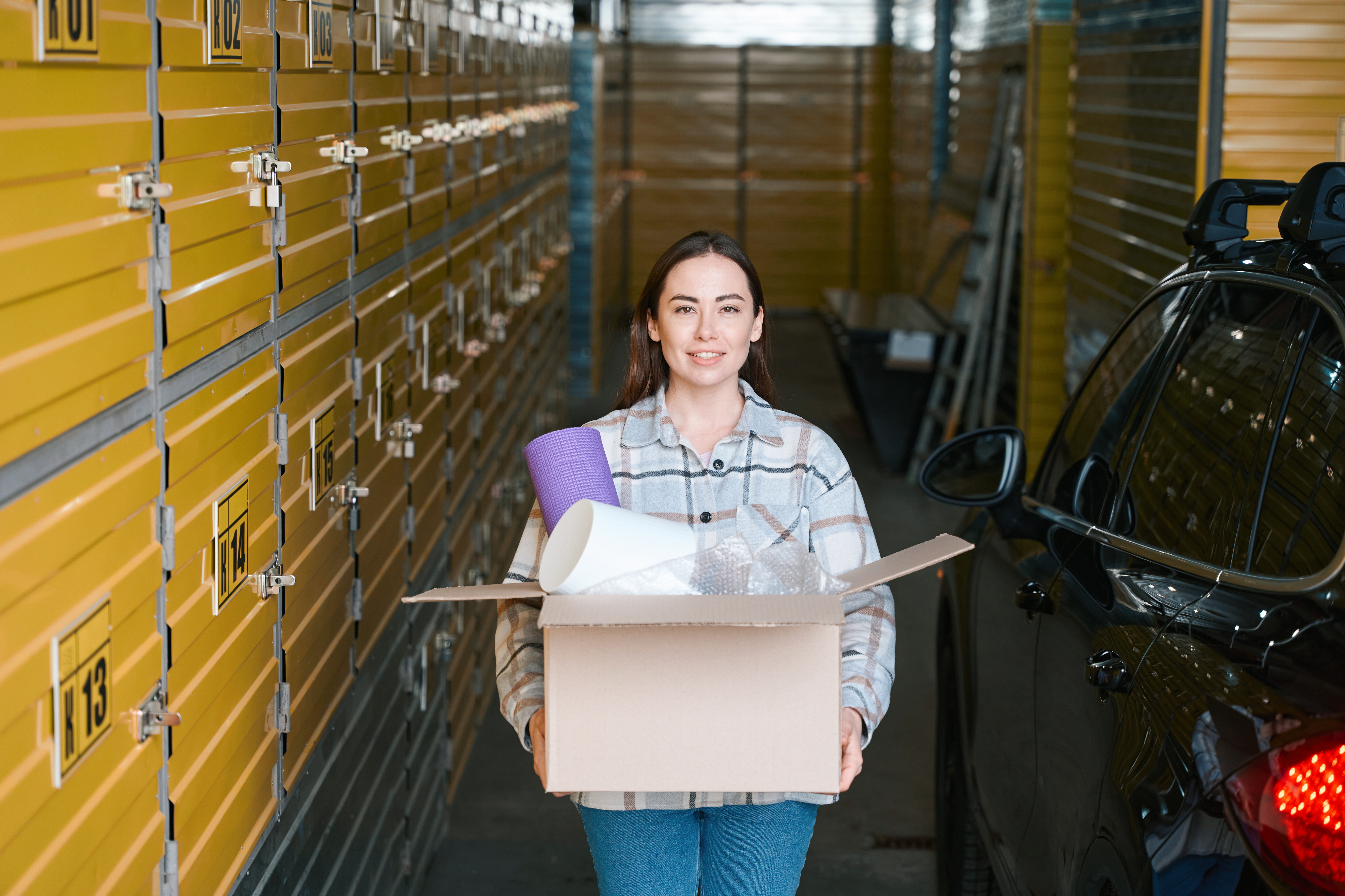 woman carrying moving box in self storage facility hallway
