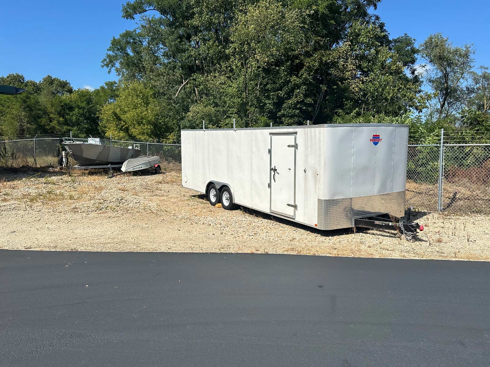 enclosed trailer and boats parked within fenced area