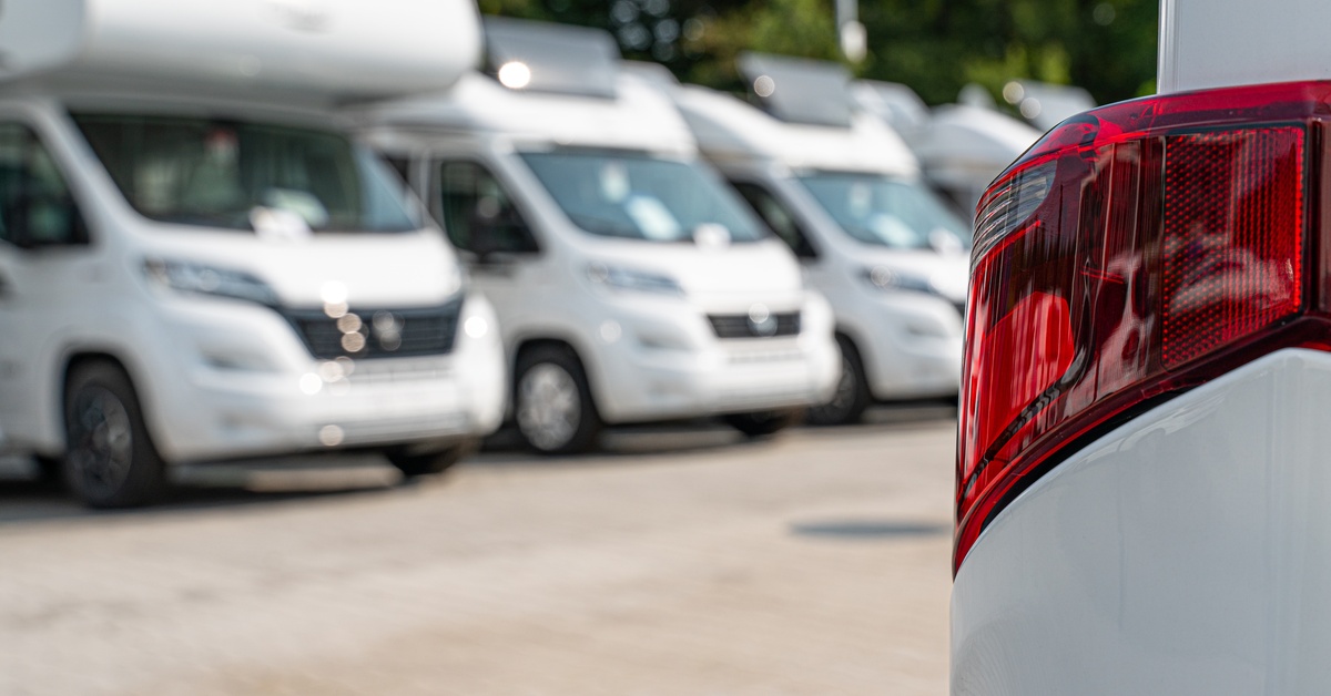 A close-up of the taillight of an RV . Three white RVs are parked in the background. A close-up of the taillight of an RV . Three white RVs are parked in the background.