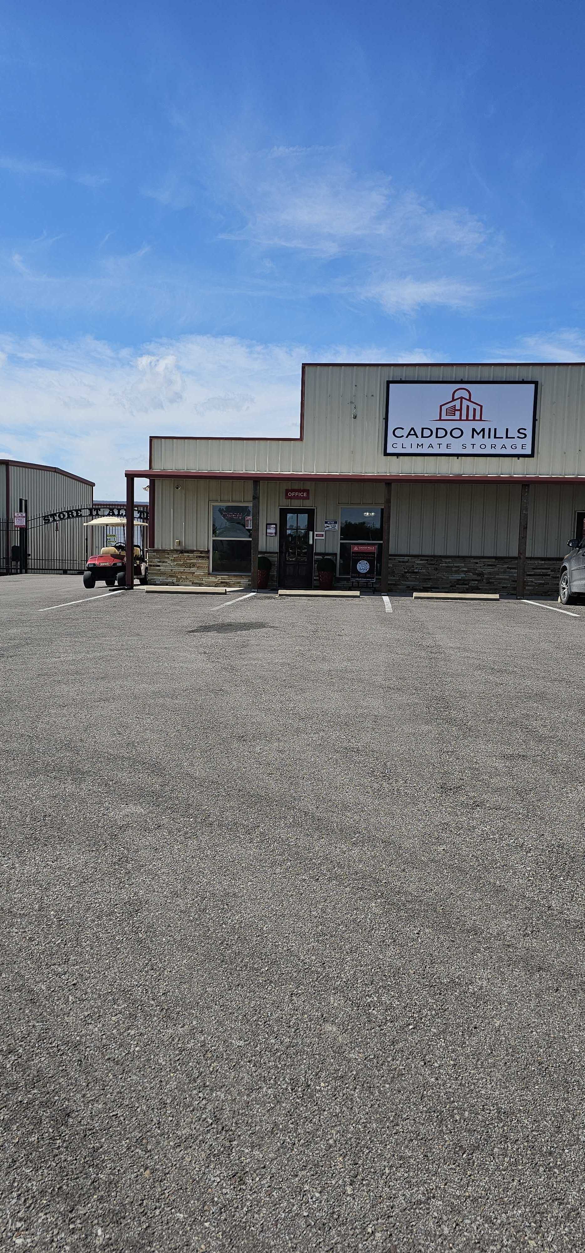 Front entrance of Caddo Mills Climate Storage facility with office, secure gate, and parking under a clear Texas sky