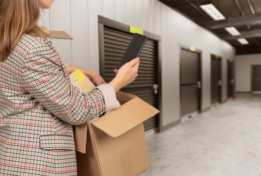 Close-up of a person carrying a moving box at a Galveston storage facility, illustrating the process of selecting the right unit size.