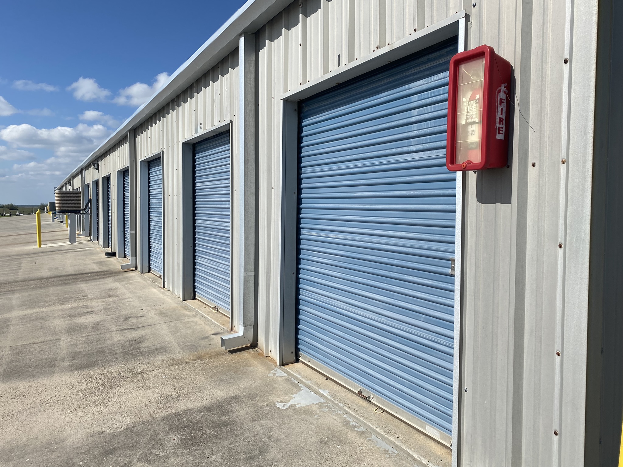 Climate-controlled self-storage units with blue roll-up doors at Bayside Storage in Galveston, TX, featuring secure concrete access and fire safety