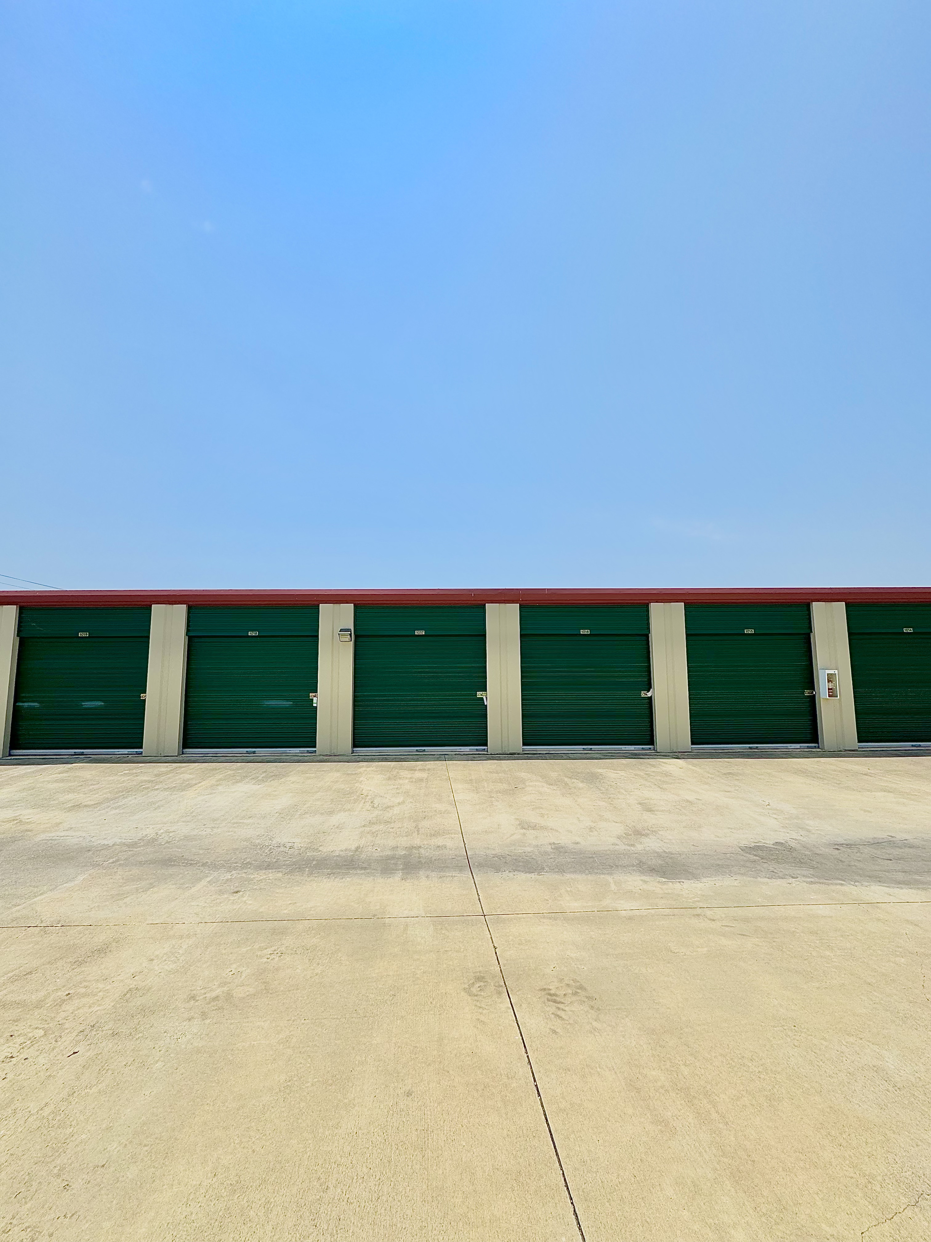 Row of secure green roll-up self storage doors at LockSmart Climate Storage facility in Lockhart, TX