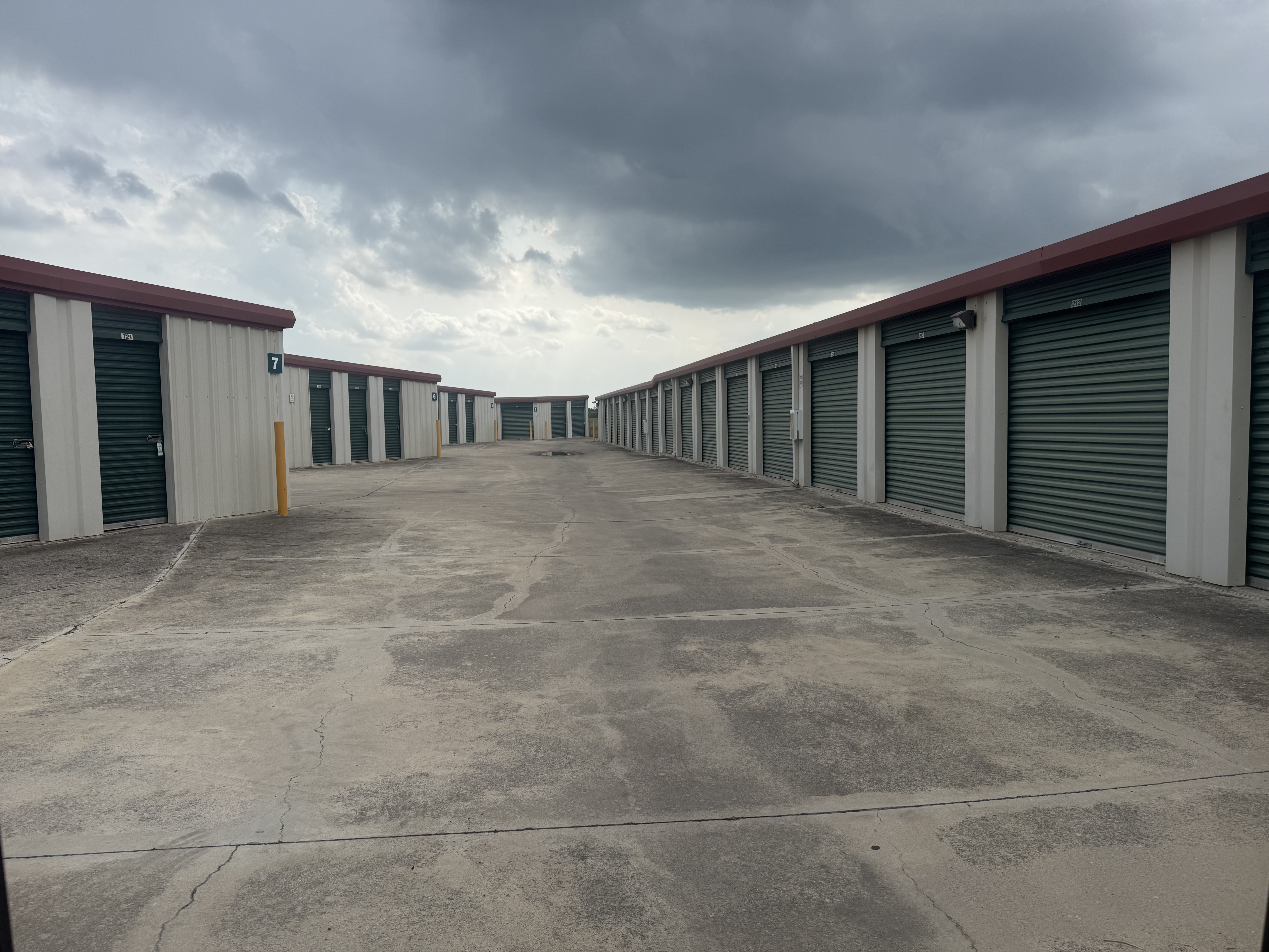 LockSmart Drive-Up Self Storage Units – Serving San Marcos College Students Drive-up self storage units with secure green roll-up doors under cloudy skies at LockSmart Storage near San Marcos, TX