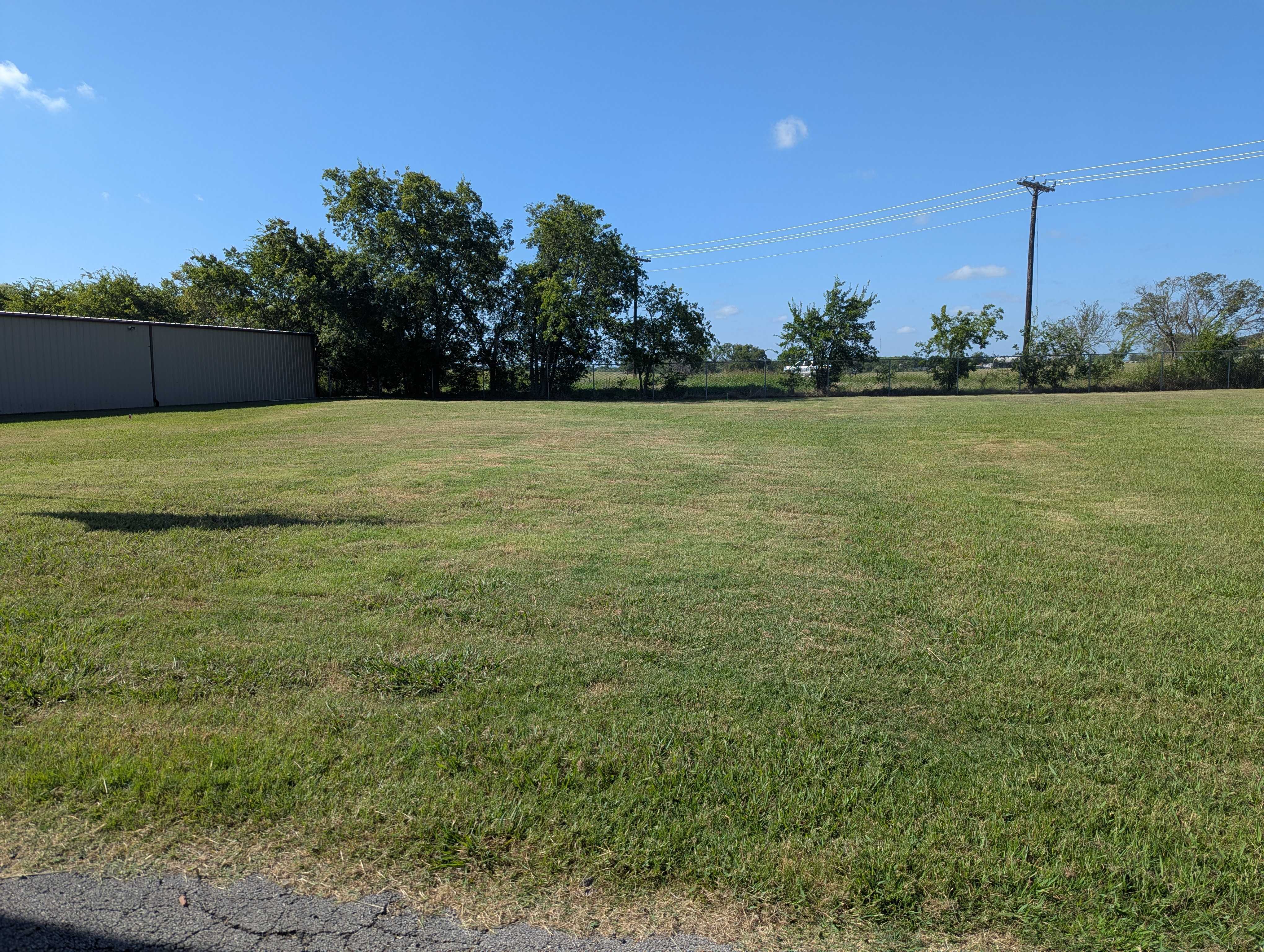 Royse City Secure Storage Facility Grounds – Extra Space for Union Valley Contractors Open grassy lot and storage building at Royse City Secure Storage near Union Valley TX, ideal for contractors needing extra space for equipment and materials.