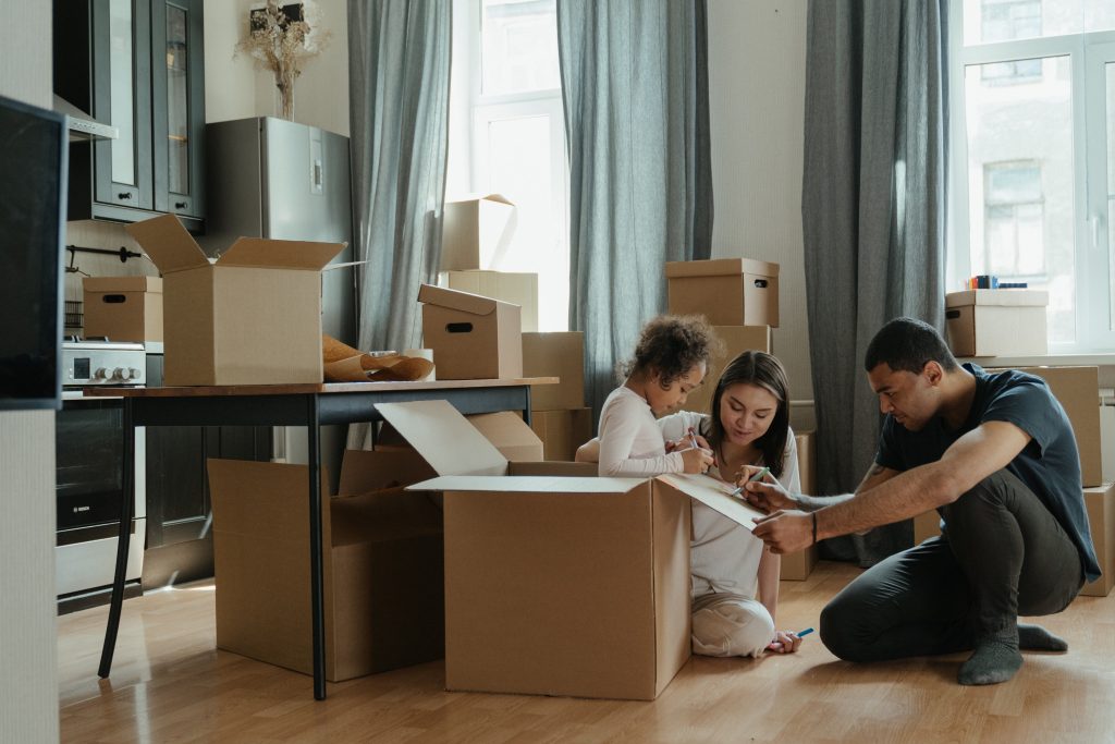 A family with a young child packing cardboard boxes in their Round Rock, TX home to prepare for a move or decluttering project.