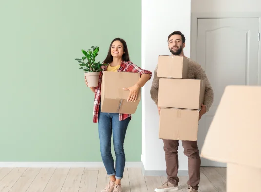 A family near Spicewood, TX, smiling while lifting a moving box, illustrating the ease of finding extra storage space for the home.
