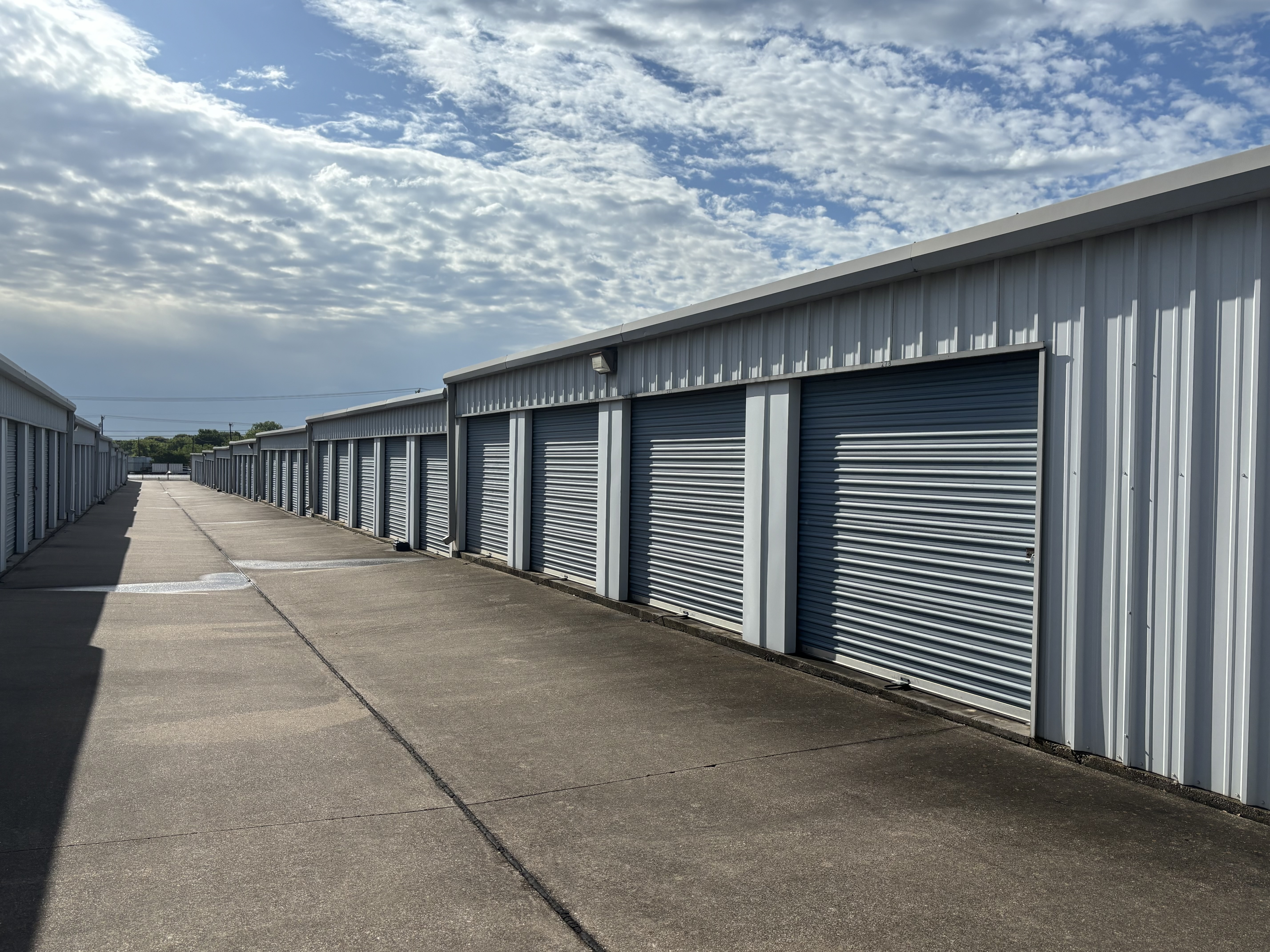 Row of drive-up self storage units at Security Self Storage and Parking in Waxahachie, TX under a partly cloudy sky