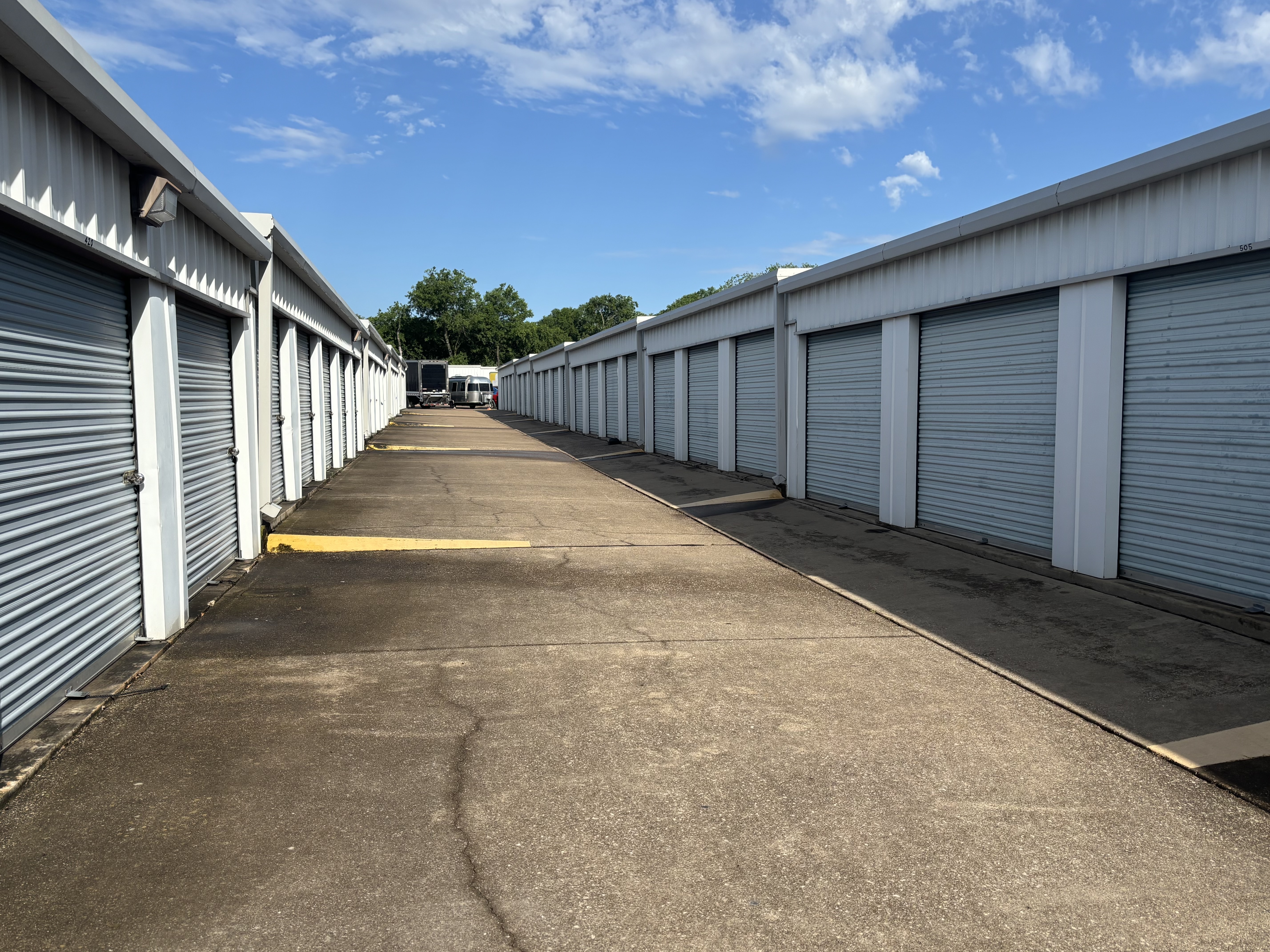 Outdoor drive-up self storage units with metal roll-up doors at a secure facility in Waxahachie, TX under a sunny blue sky