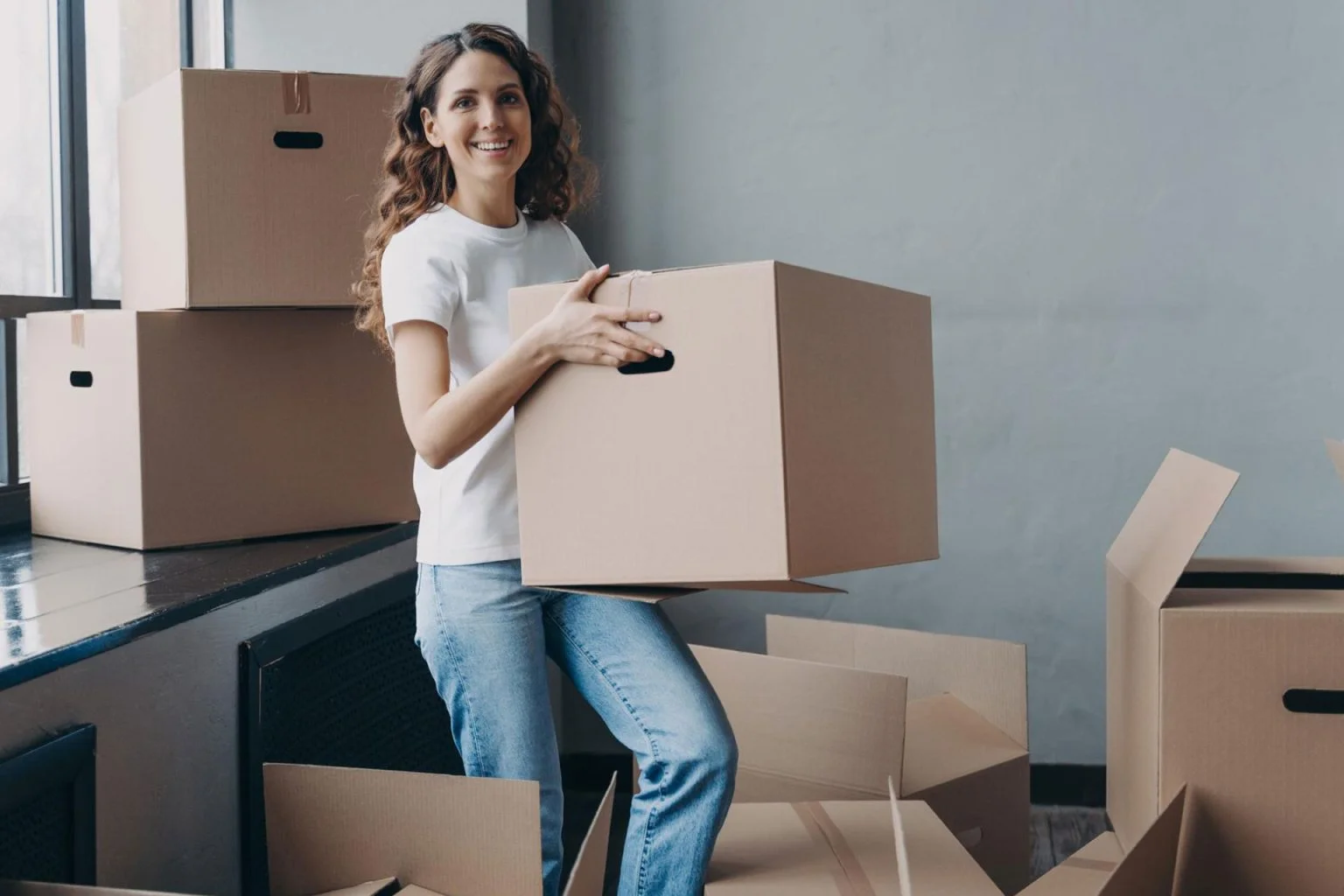 A customer smiling while carrying boxes through a clean, secure storage facility near Waxahachie, illustrating professional facility monitoring.