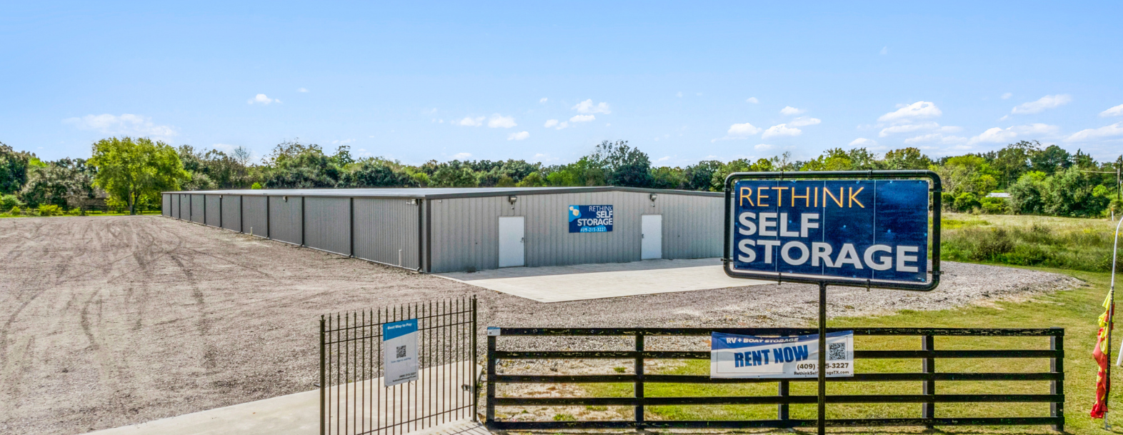 Exterior view of Rethink Self Storage in Hamshire, TX, featuring a spacious layout with a large climate-controlled storage facility, secure gated entrance, and prominent signage advertising RV and boat storage options.