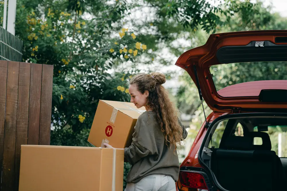 A young student removing boxes from her red car