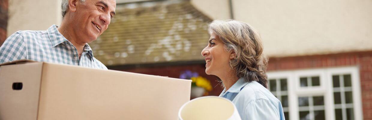 older couple with moving boxes outside home