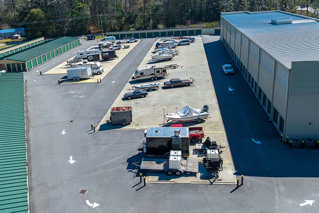 Aerial view of an outdoor storage facility with parked RVs, boats, and trailers between storage buildings.