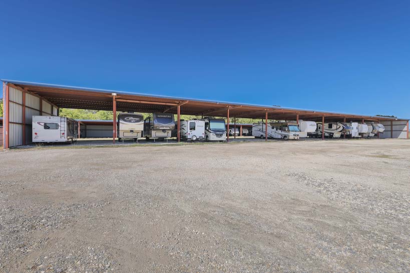 RVs and trailers under a long covered parking row