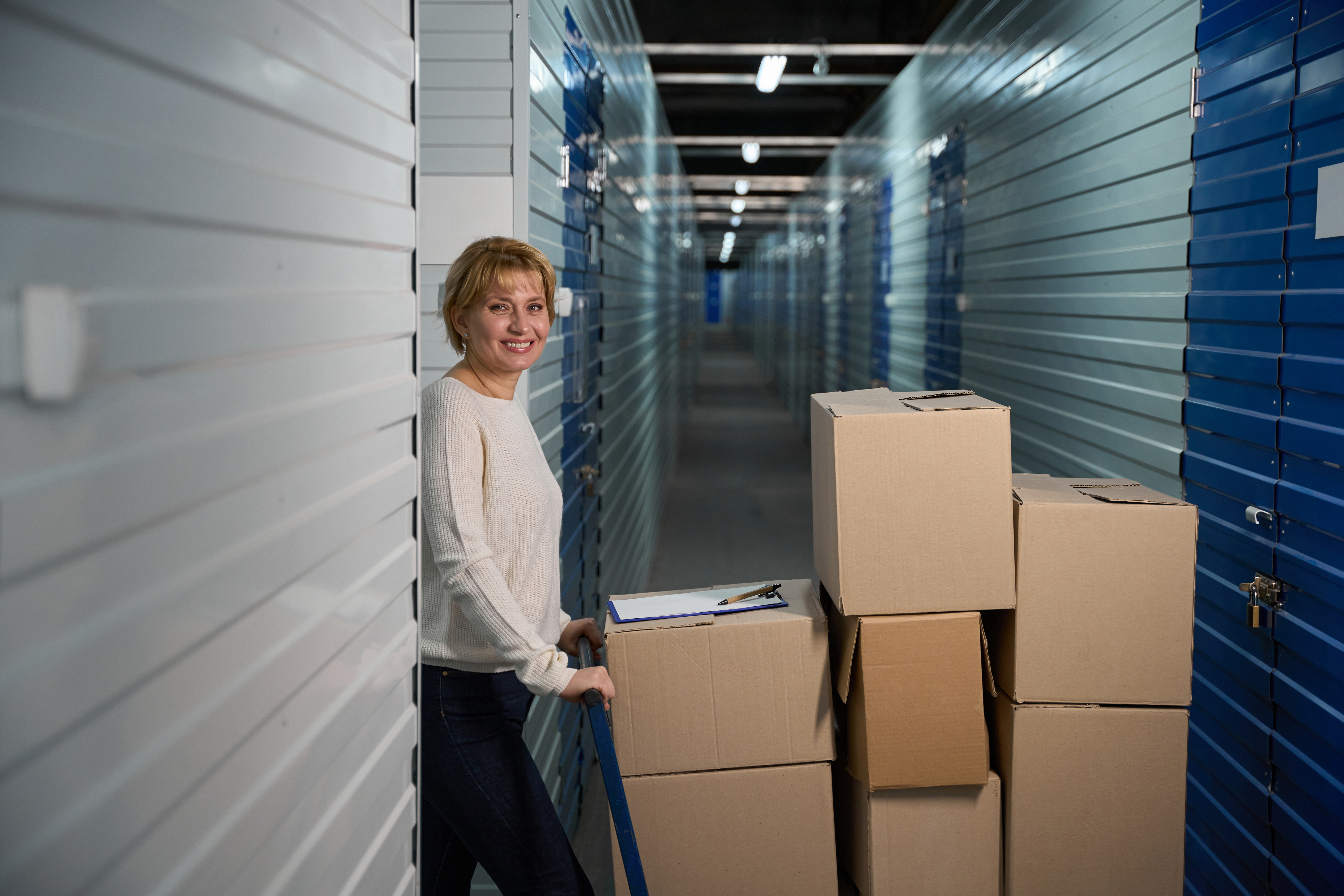 Woman moving boxes into a storage unit hallway