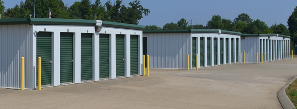 Three self storage buildings, each with unit doors facing left and traffic pillars around their corners