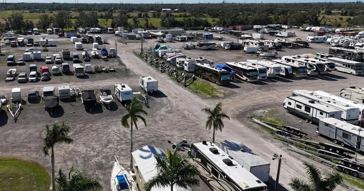 Boat and RV storage facility with multiple vehicles and trailers parked outdoors