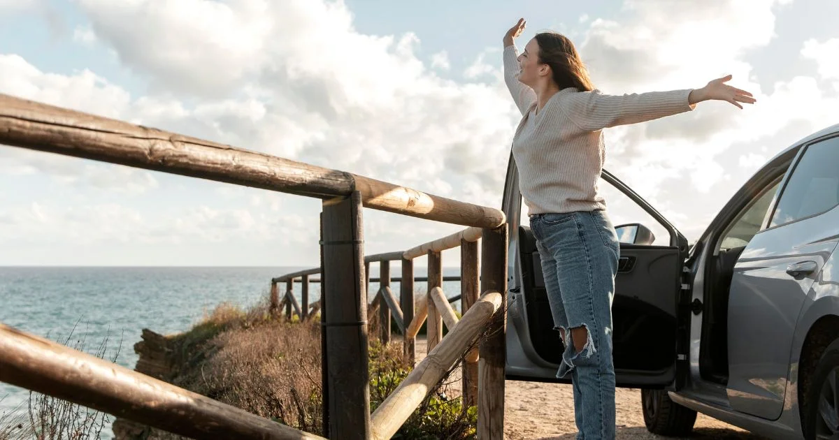 Woman by ocean with car door open