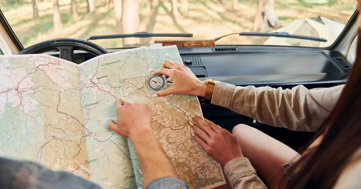 Couple using a map and compass inside RV while planning a camping trip