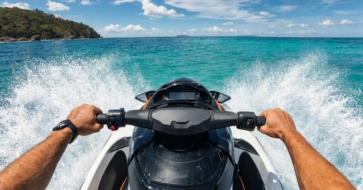 Person riding jet ski across turquoise ocean water