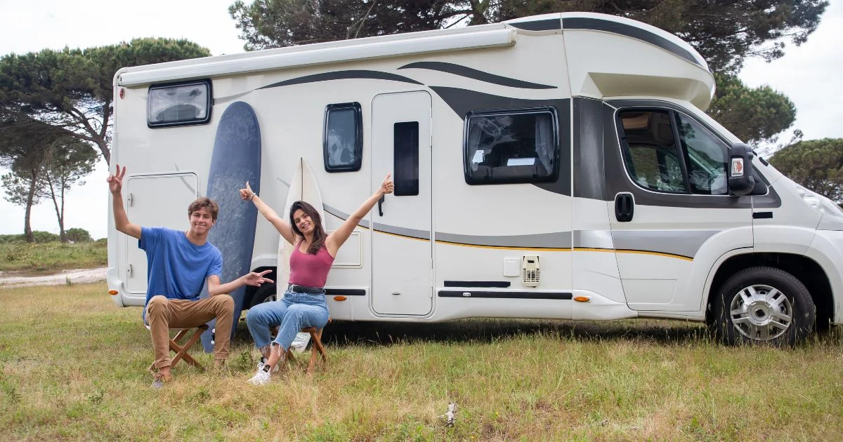 Couple sitting outside RV camper on road trip