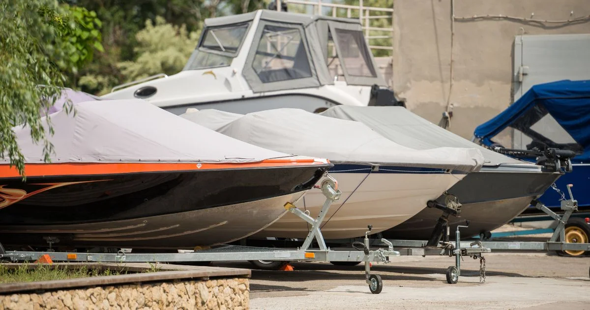 Covered boats stored on trailers in outdoor lot