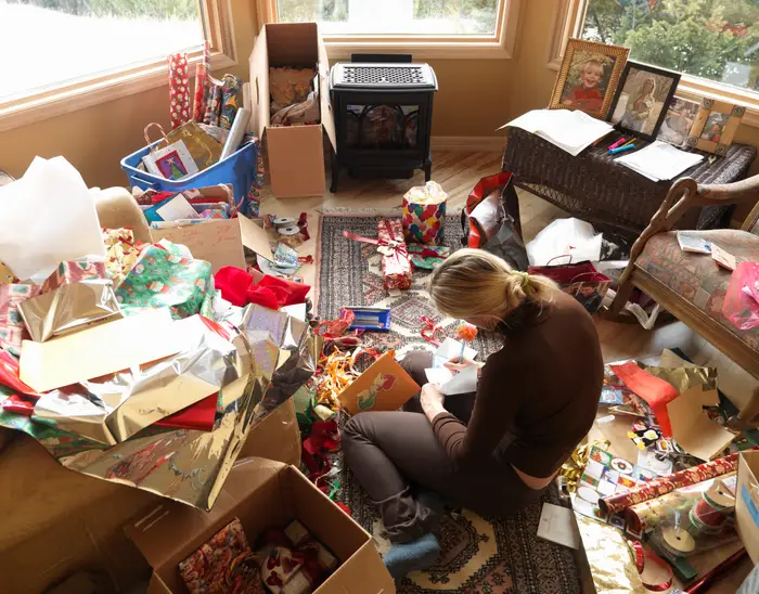 blonde person writing on a card while wrapping presents