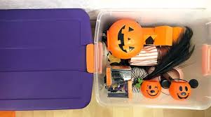 Storing Halloween Decor Isn't Scary When You Use A-Verdi Self Storage Plastic storage bin filled with Halloween decorations including pumpkin buckets, costumes, and festive accessories, ideal for seasonal storage and organization.