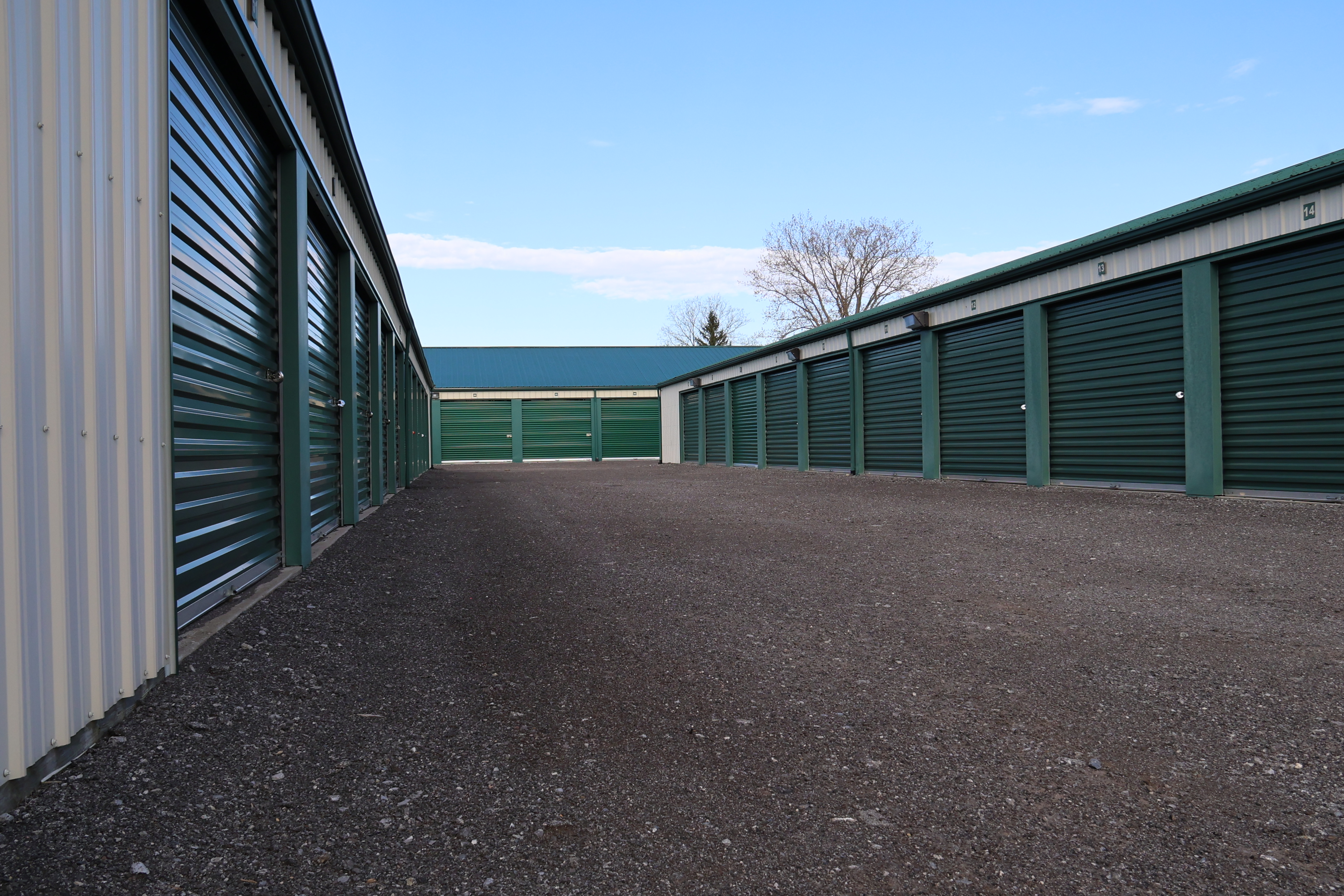 Wide drive aisle between outdoor storage units at A-Verdi Self Storage Darien Center with green roll-up doors