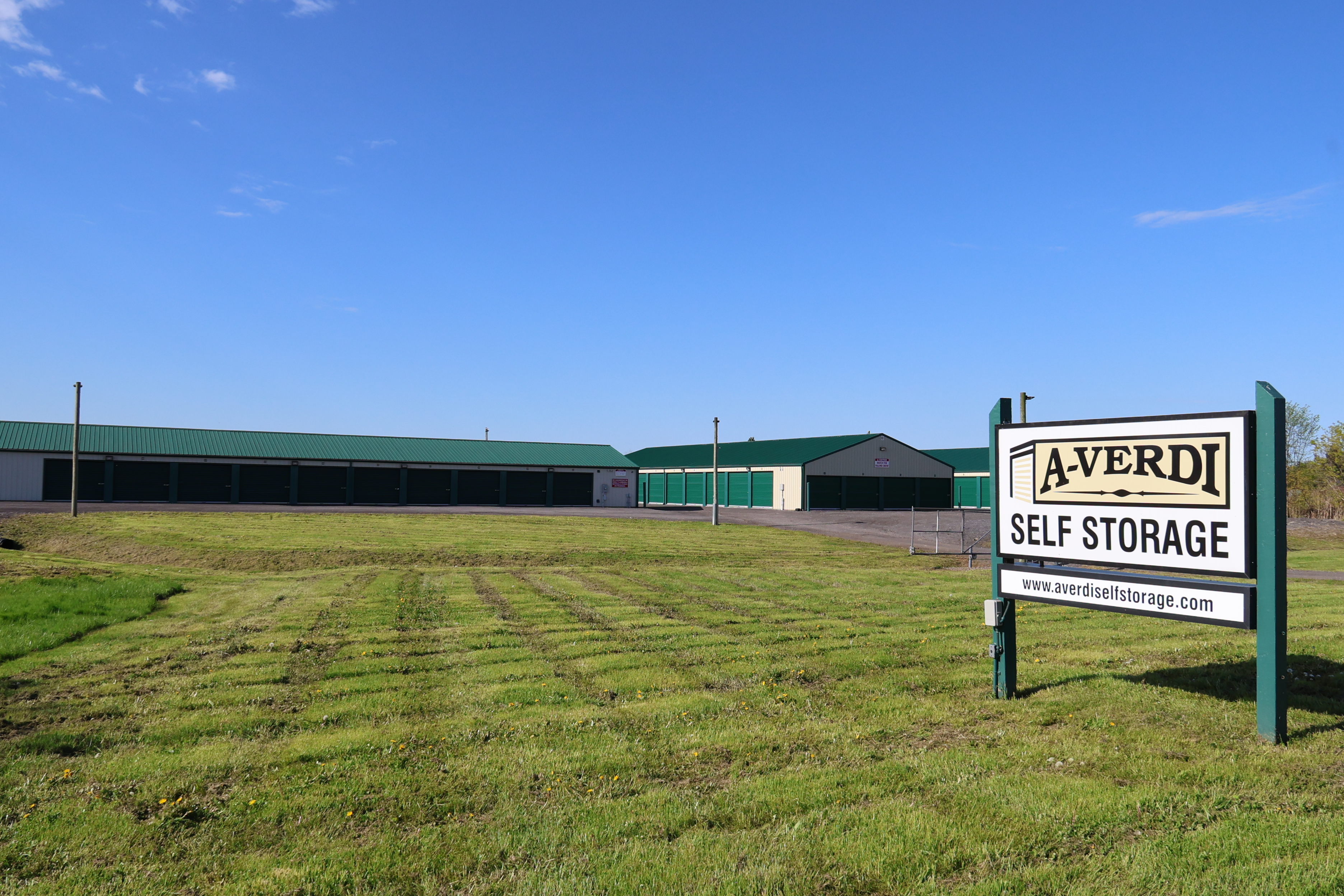 A-Verdi Self Storage Darien Center sign with view of the facility and outdoor storage buildings in the background