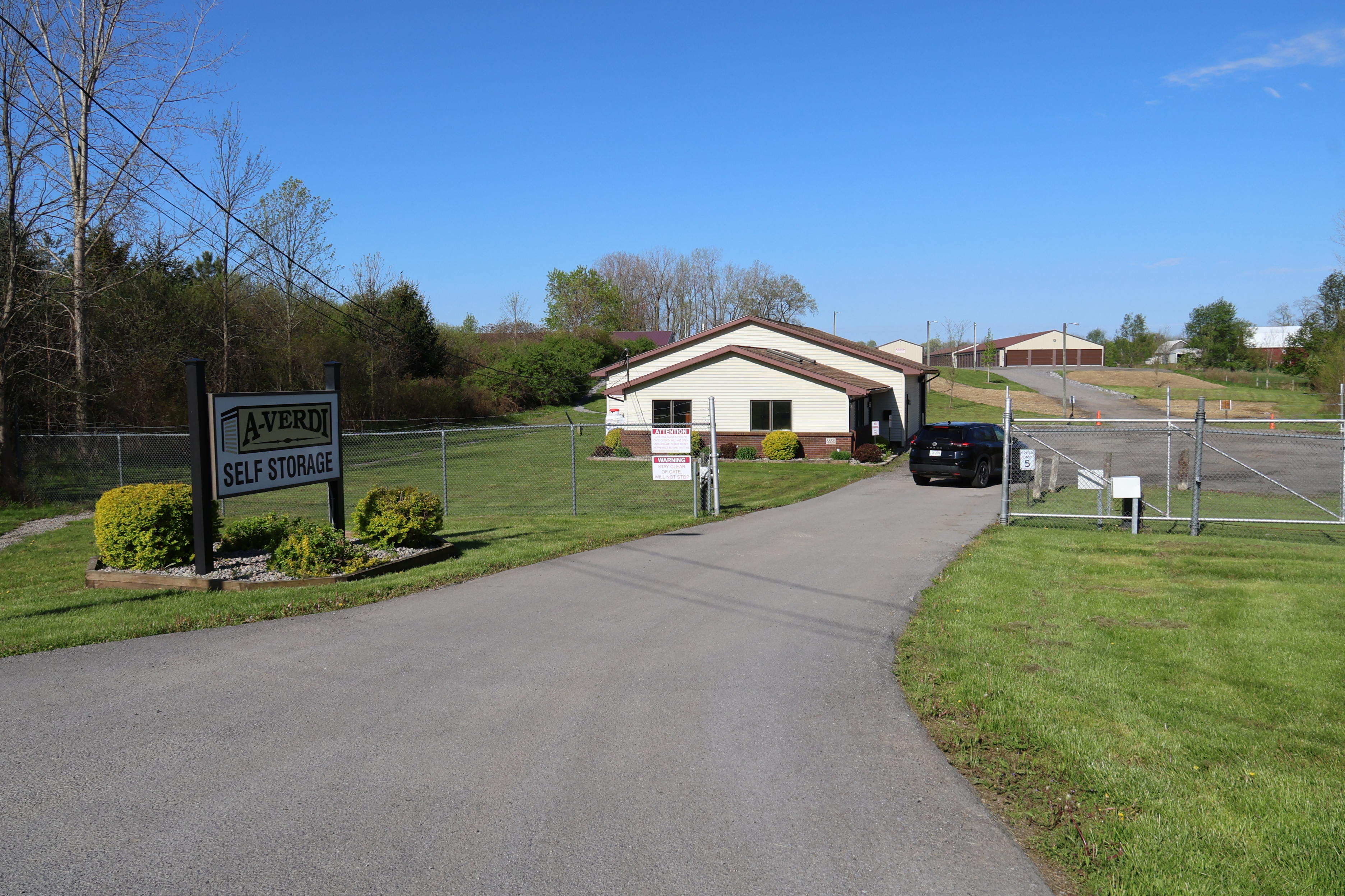 A-Verdi Self Storage Batavia facility entrance with secure gated driveway and branded sign on a clear day