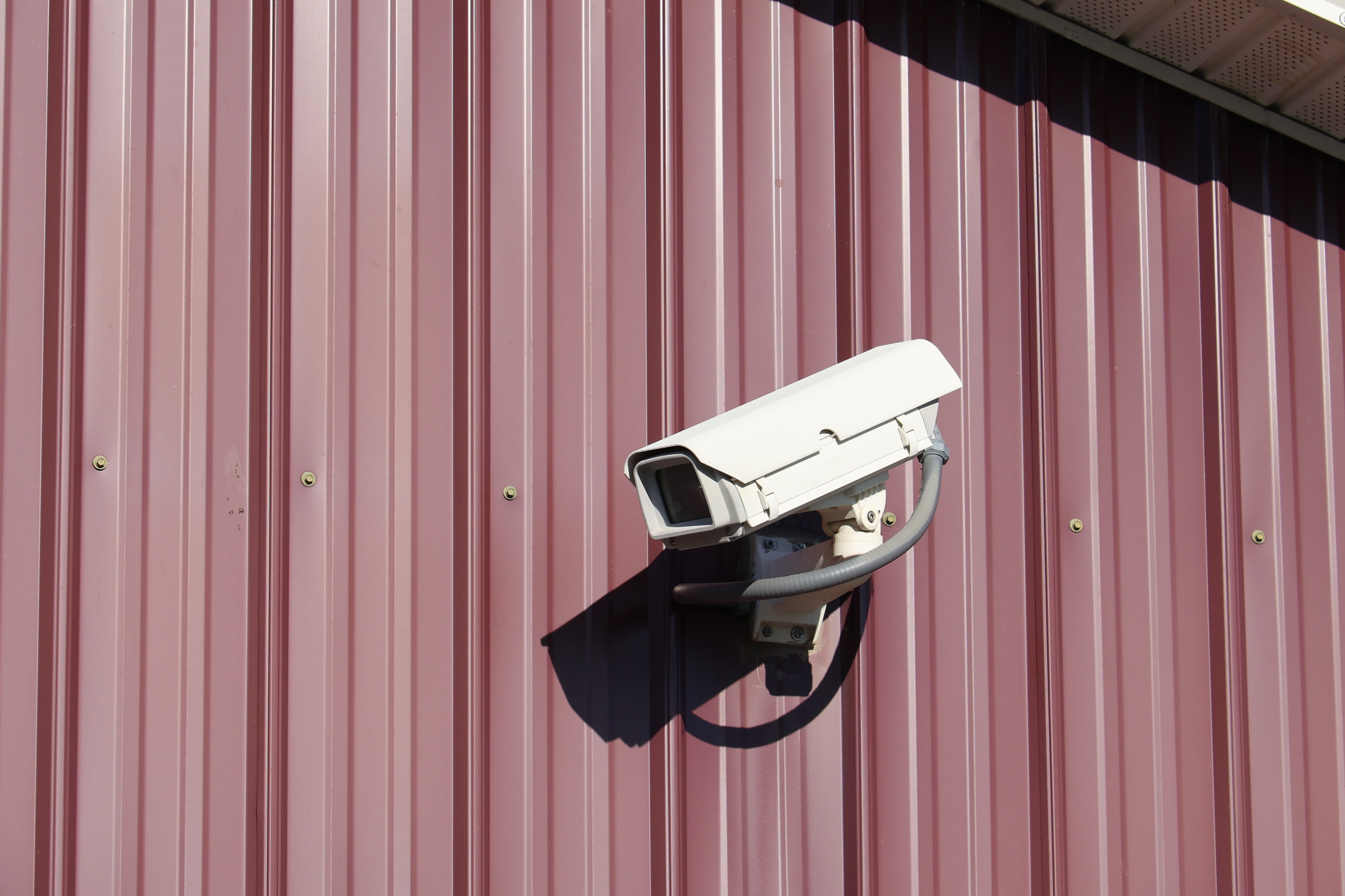Security camera mounted on a red metal building at A-Verdi Self Storage Syracuse for on-site property monitoring