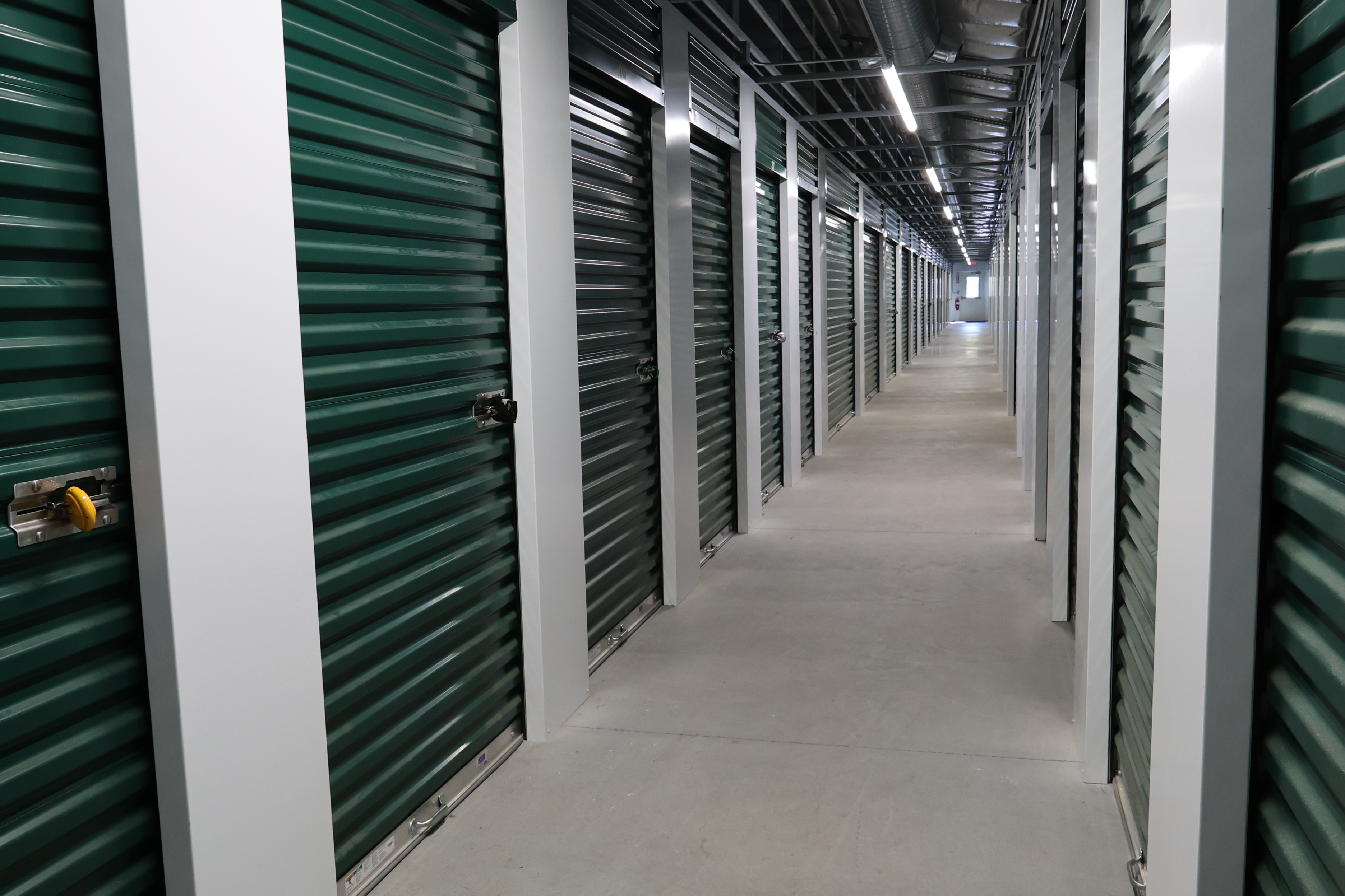 Indoor storage corridor at A-Verdi Self Storage Clay with secure roll-up doors and bright overhead lighting