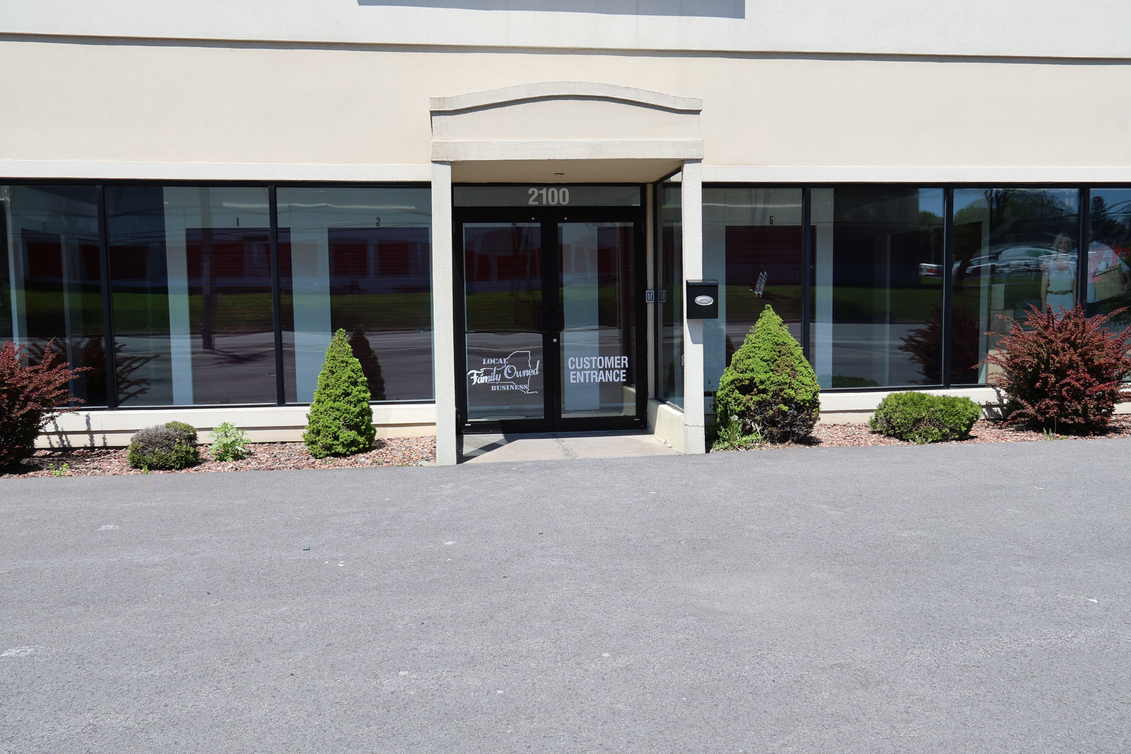 Customer entrance at A-Verdi Self Storage Utica office with glass doors, landscaping, and clear signage