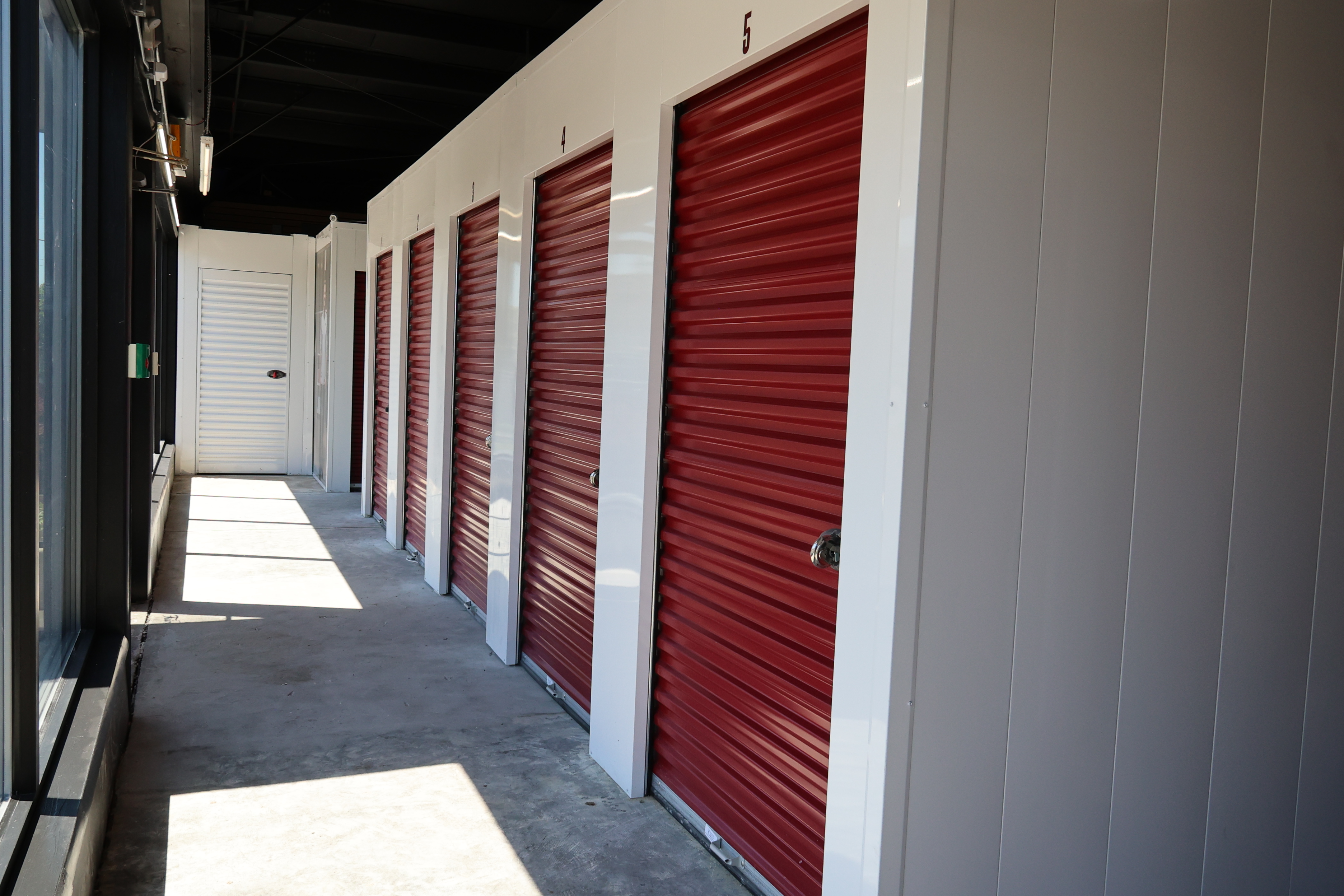 Interior hallway of A-Verdi Self Storage Utica featuring individual storage units with red roll-up doors