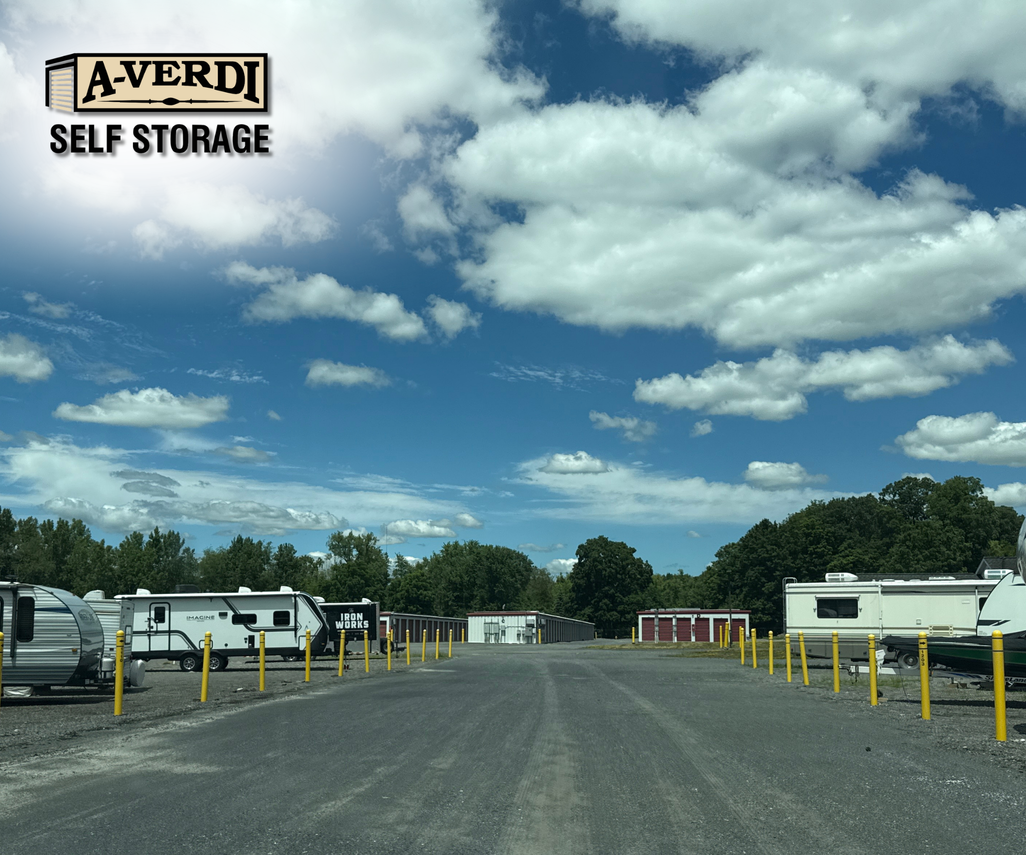 A-Verdi Self Storage outdoor vehicle storage lot with RVs and trailers parked along a gravel drive under a bright blue summer sky.