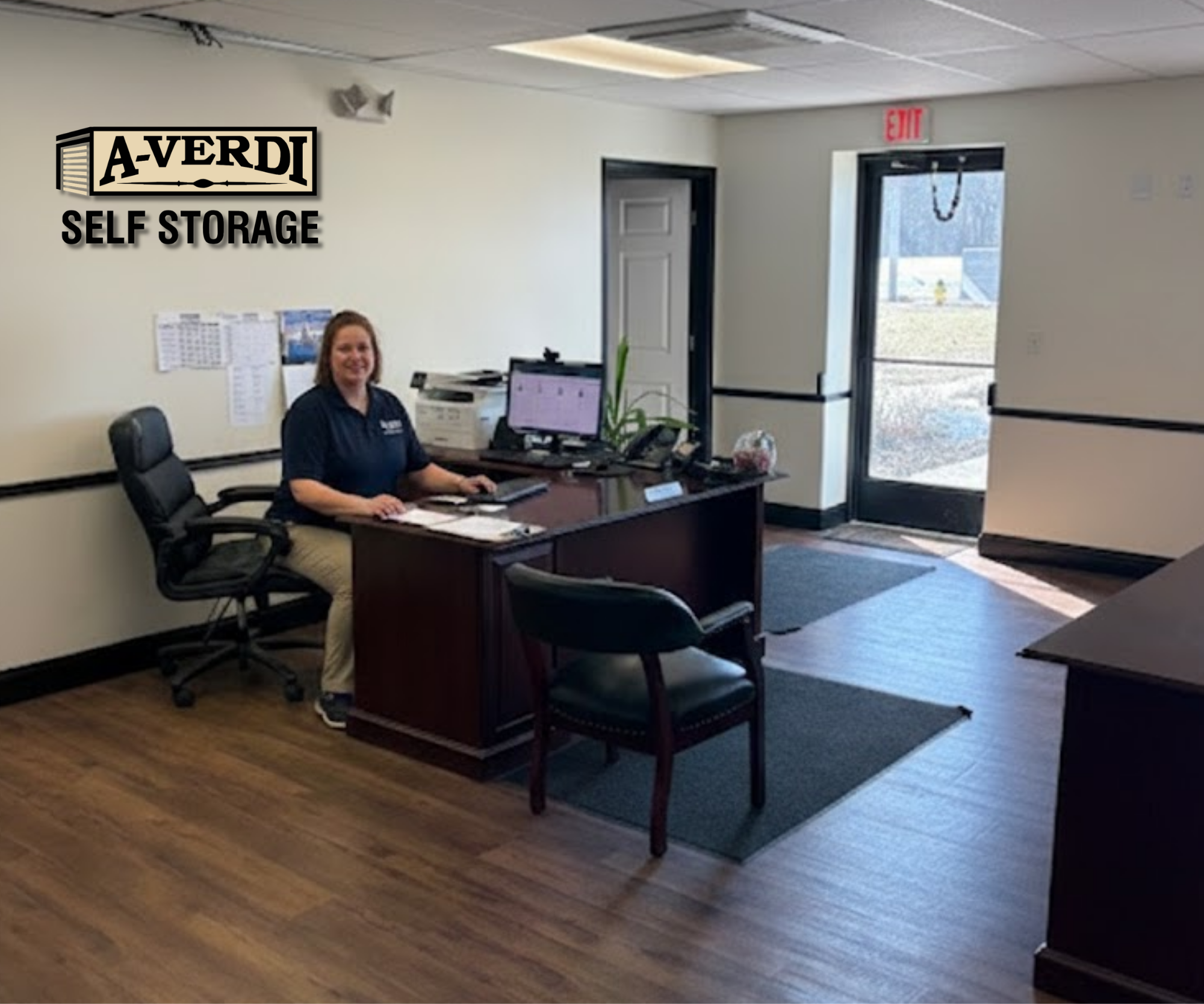 Meet the A-Verdi Team: Our Commitment to Community Starts With People A-Verdi Self Storage employee sits at a desk in a facility office, smiling at the camera