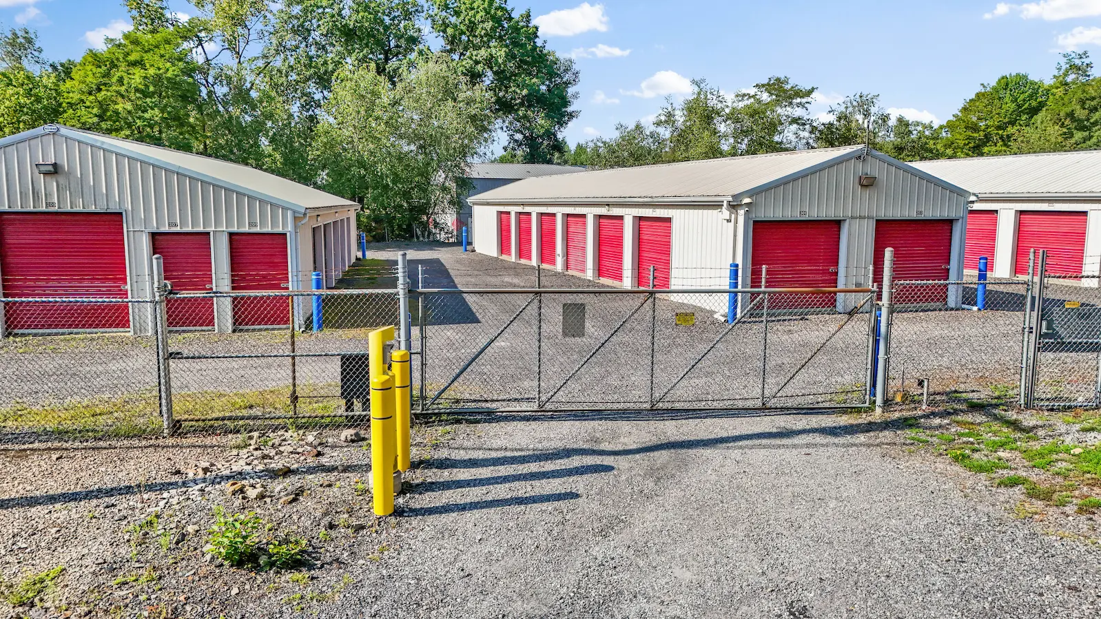 Gated entrance to UrbanLock self-storage facility in Scranton with secure chain-link fence, multiple climate-controlled storage buildings, and bollard security barriers