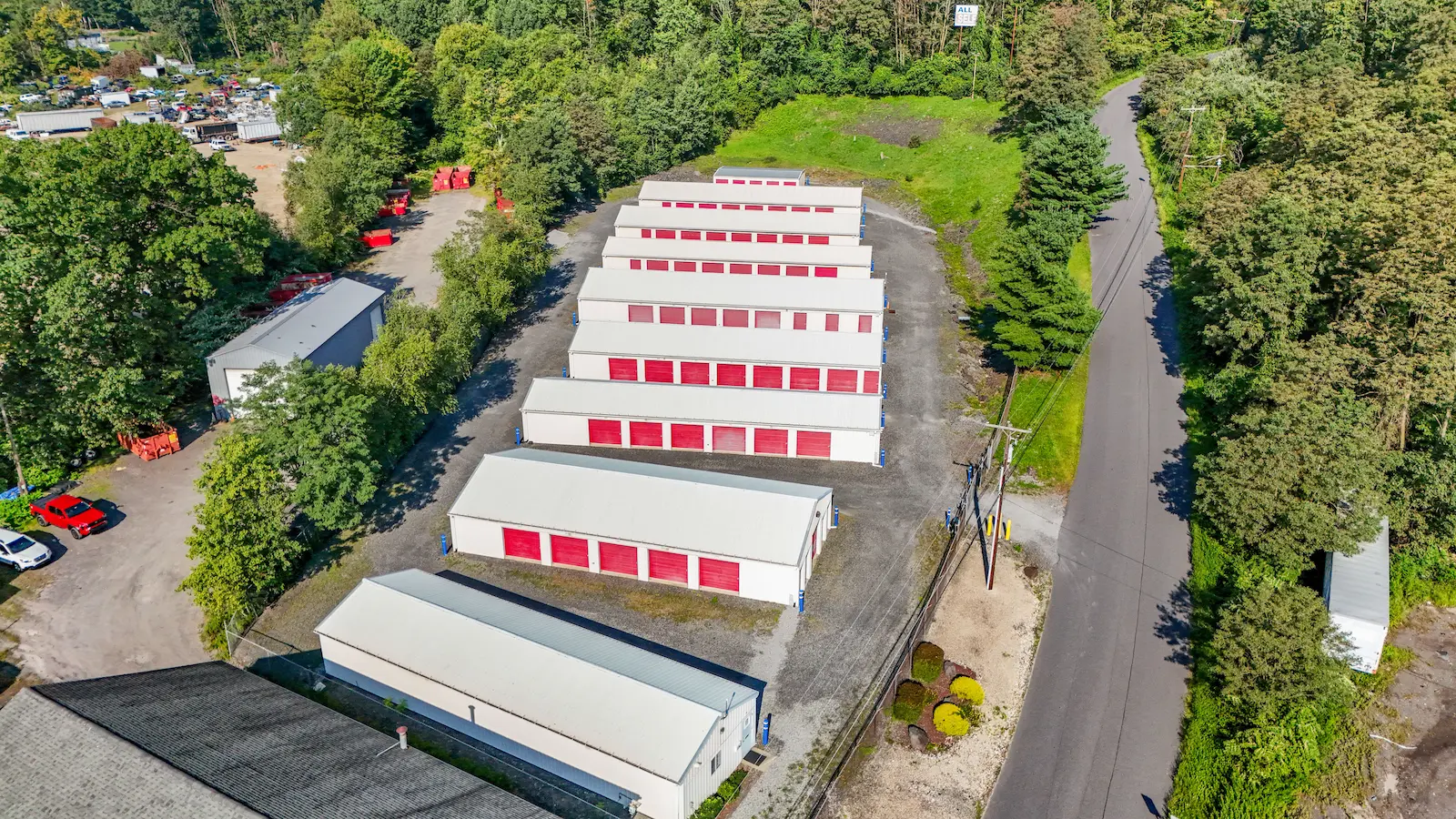 Aerial view of UrbanLock self-storage facility in Scranton showing organized storage building rows surrounded by dense forest, with adjacent industrial properties visible
