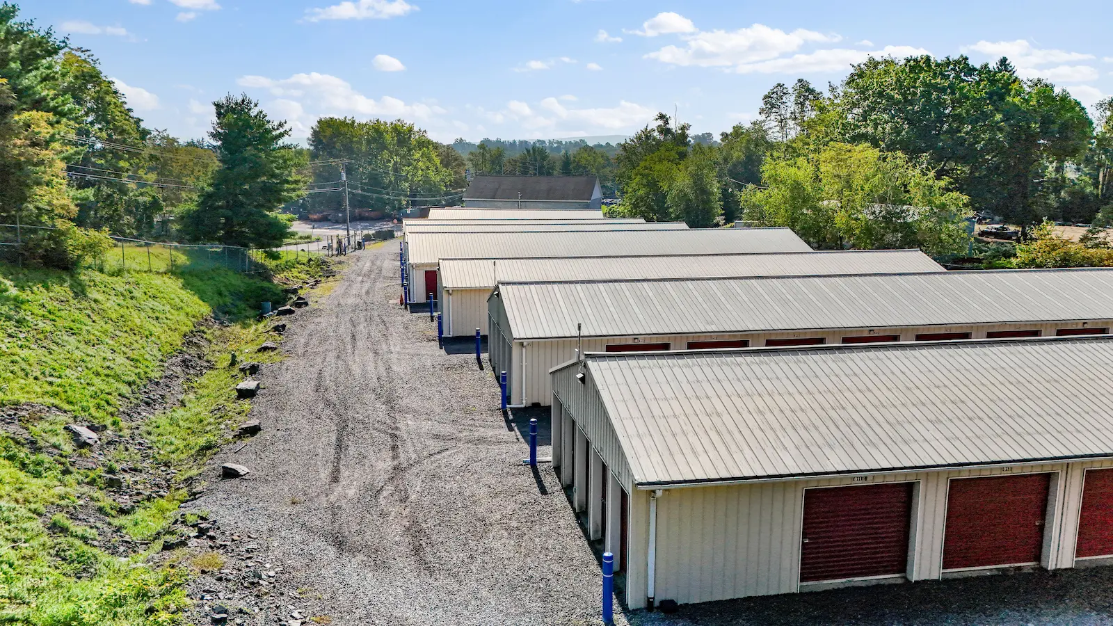 Drive-up storage units at UrbanLock in Scranton with access lane view, showing multiple buildings and wooded landscape in background