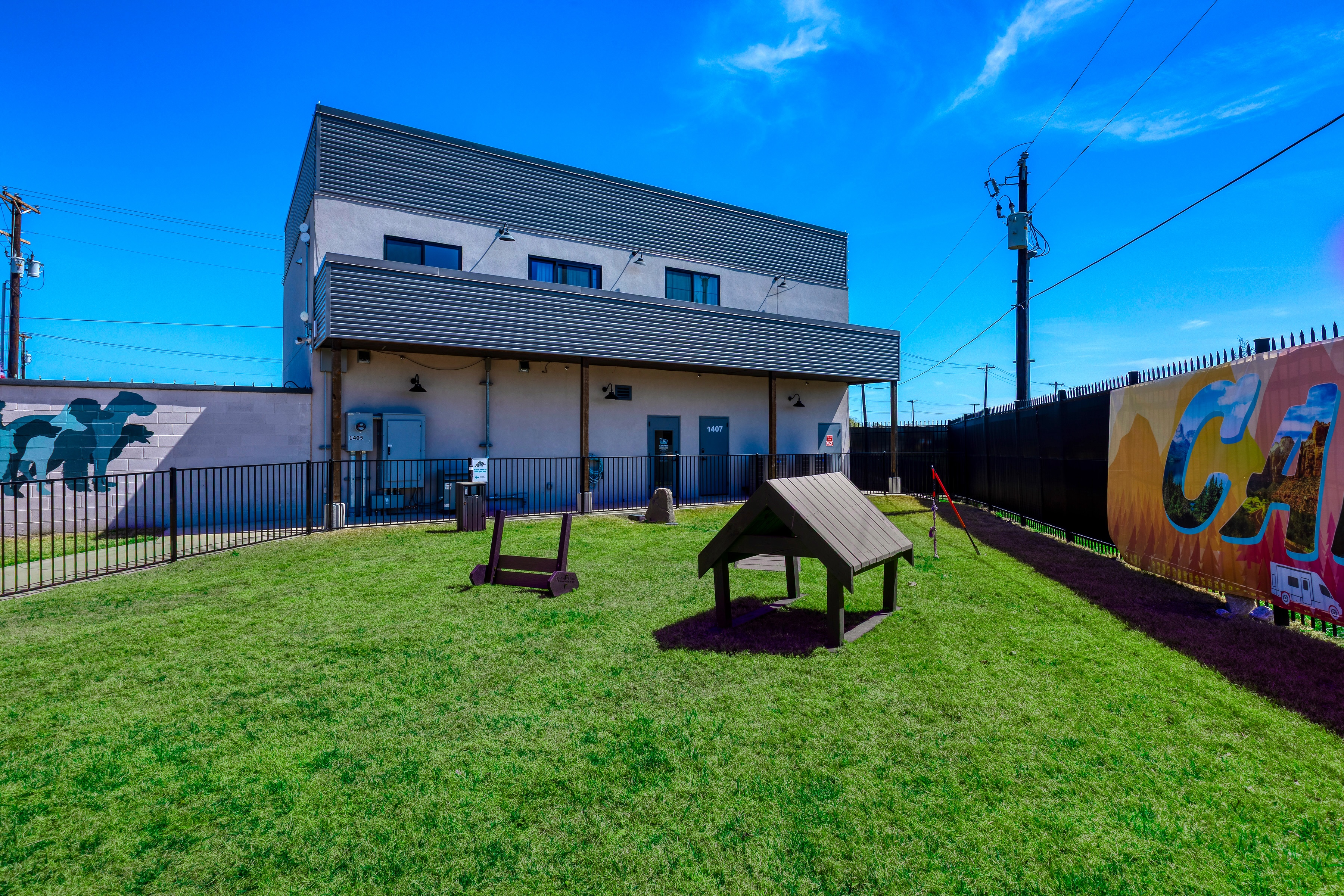 Dog park with grass, pet play structures, and mural near Carefree Wylie office