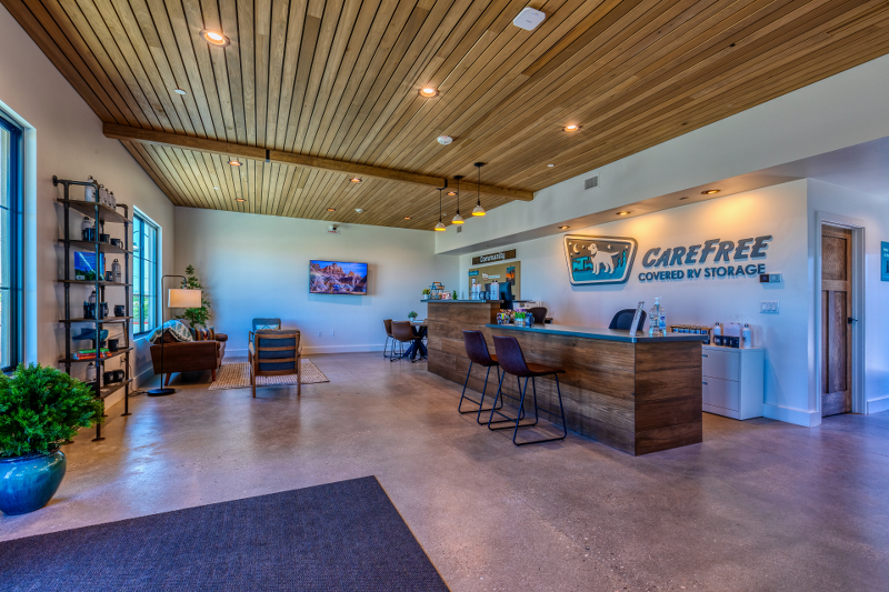 Modern and welcoming interior of the Carefree Covered RV Storage welcome center in Maricopa, Arizona, featuring a sleek front desk, comfortable seating area, and wood-accented ceiling—designed to enhance the customer experience for RV, boat, and trailer storage clients.