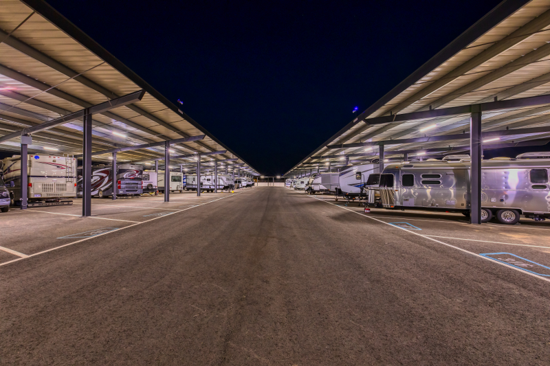 Well-lit covered RV storage at night at Carefree Covered RV Storage in Maricopa, Arizona, showcasing bright overhead lighting, wide drive aisles, and premium protection for motorhomes, fifth wheels, and trailers—ideal for 24/7 access and enhanced nighttime security.