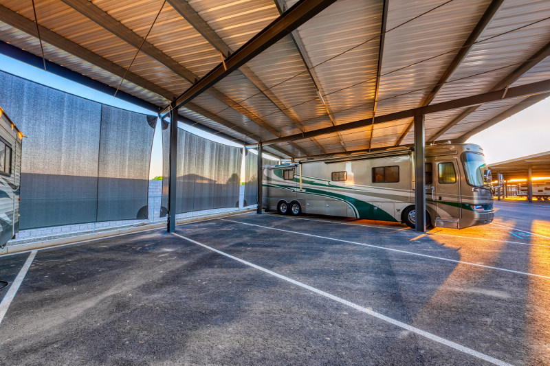 Premium covered RV storage space at Carefree Covered RV Storage in Maricopa, Arizona, featuring protective side shade screens, wide parking stalls, and steel canopy construction—ideal for shielding Class A motorhomes and large vehicles from sun and weather damage.